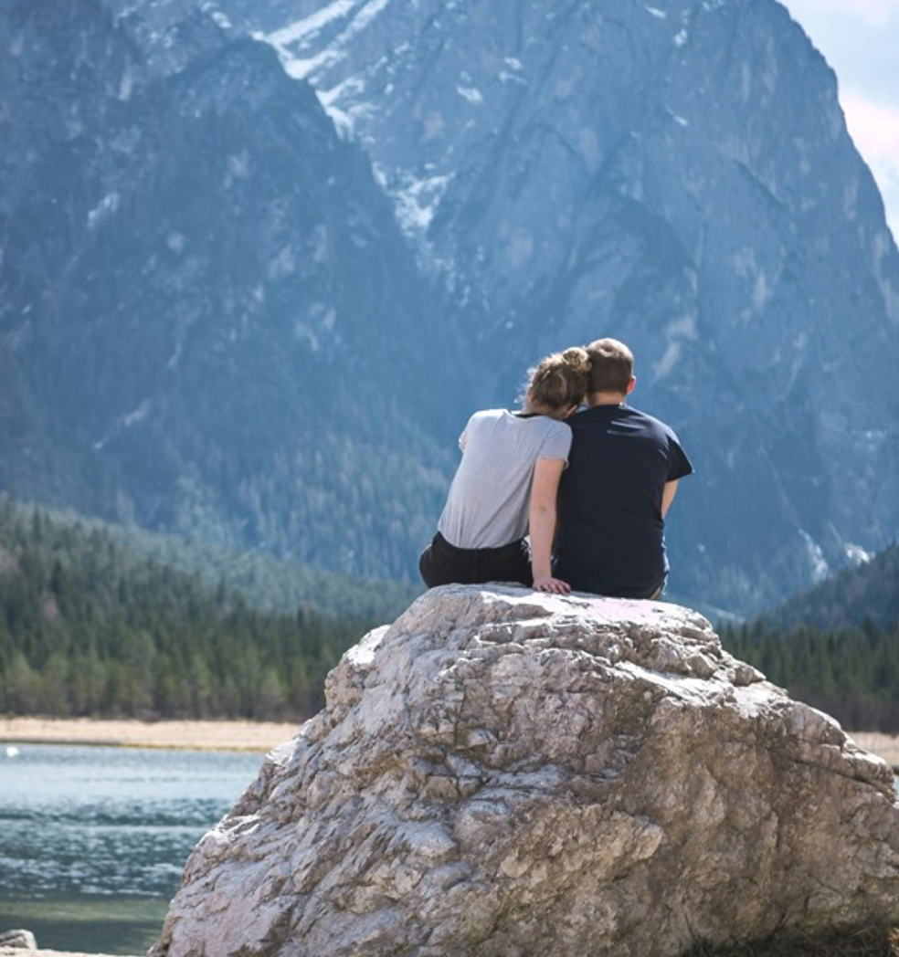 Couple sitting on a rock near a lake